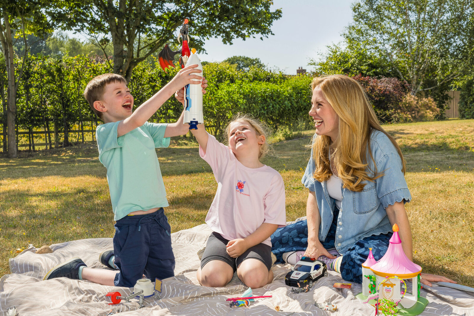 Maddie Moate laughing with a boy and girl as they launch a Playmobil rocket together